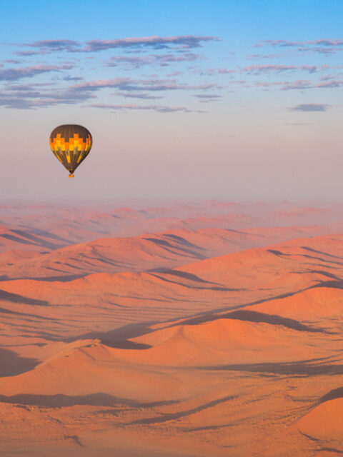 Žltý teplovzdušný balón letí nad modrou oblohou – symbol dobrodružstva a nezabudnuteľných výhľadov.