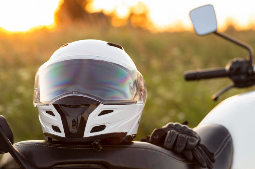 Motorkár v kompletnej ochrannej výbave s prilbou, motorkárskou bundou, rukavicami, nohavicami a vysokými čižmami stojí pri motocykli.